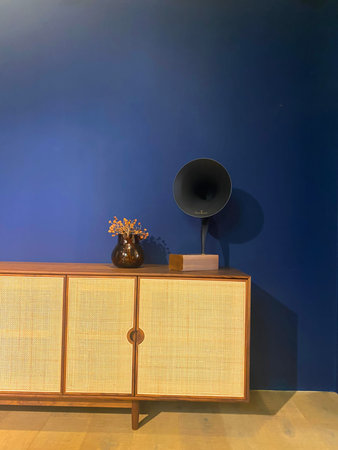 Wooden commode with speaker and vase on blue wall background
