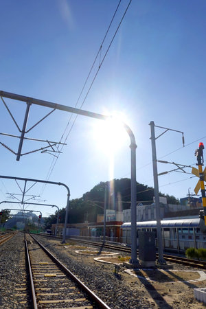 Railway station platform with blue sky and sun in the background.