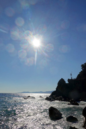 Rocks in the sea and the sun in the blue sky.