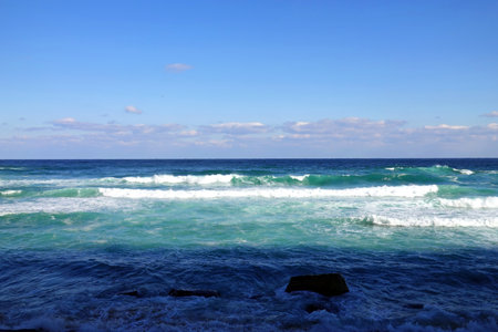 Waves breaking on the rocks on the seashore against the blue skyの写真素材
