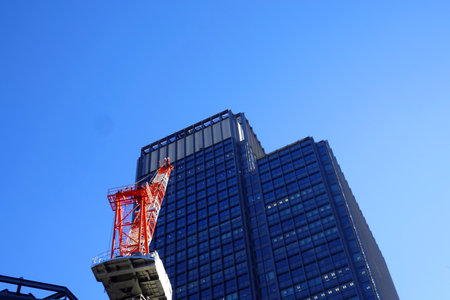 Tower crane and building under blue sky, closeup of photoの写真素材