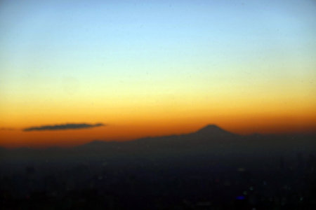 Sunset over the city with silhouettes of mountains in the backgroundの写真素材