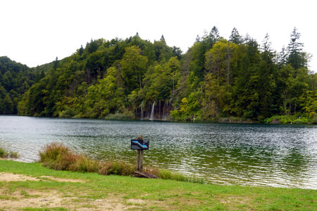 Lake in the forest with a signpost and waterfall in the backgroundの写真素材