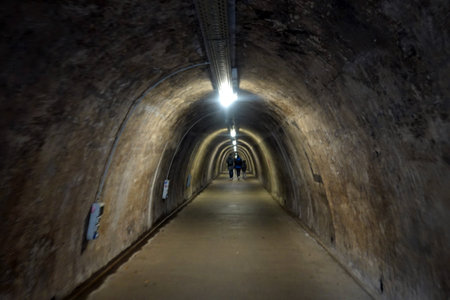 Underground tunnel with light at the end of the tunnel with people walkingの写真素材