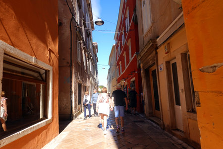 Unidentified people walk along the narrow street in Venice, Italy. Venice is one of the most visited tourist destinations in the world.の写真素材