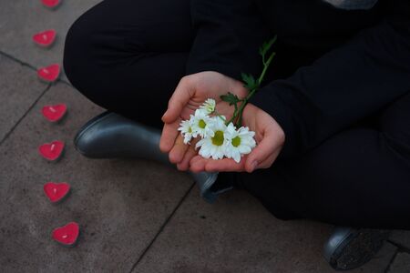 On mother's day, the boy is waiting for his mother with the daisy flowers in his hand.の写真素材