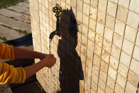 little girl washing her hands at the fountain. street fountain