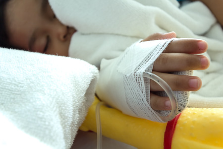 Illness asian kids asleep on a sickbed in hospital, saline intravenous IV on handの写真素材