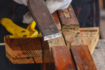 The hand of the asian carpenter taking the chisel to sharpen the wood plank