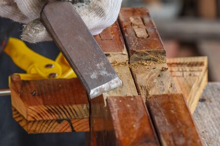 The hand of the asian carpenter taking the chisel to sharpen the wood plankの写真素材