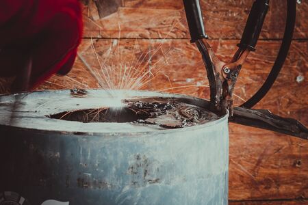 Worker with red glove to protect spark light with welding Process with blue tube metal and bright sparks in steelの写真素材