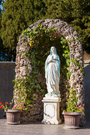 Statue of holy martyress in churchs cortyard with flowersの写真素材