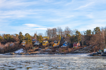 Color wooden cabins on the shore with frozen sea at the foreground. Scandinavian styleの写真素材