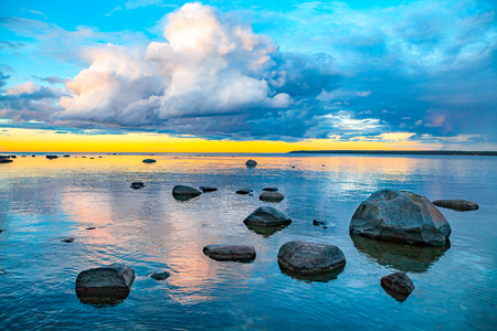 Bright colored sea sunset with stones along the coastの写真素材