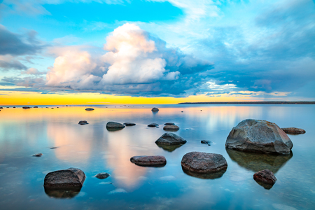 Bright colored sea sunset with stones along the coastの写真素材