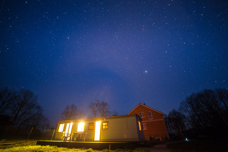Night shot of small illuminated cabin and starry sky.の写真素材