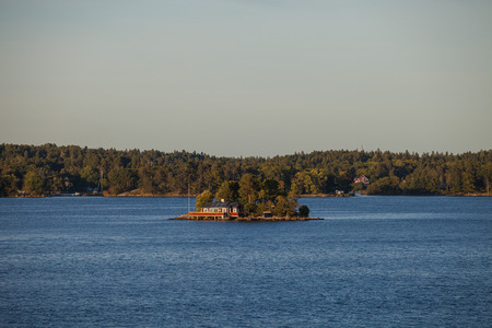 View on lonely island in Stockholm archipelago, Sweden. Private hut and pier. Summer sunset time.の写真素材