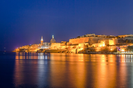 Summer deep night view of Valetta profile over sea. Long exposure. Illuminated architecture.の写真素材
