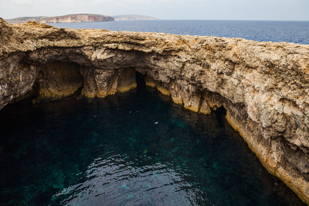 Limestone rocks of Malta coast. Hidden water cave.の写真素材
