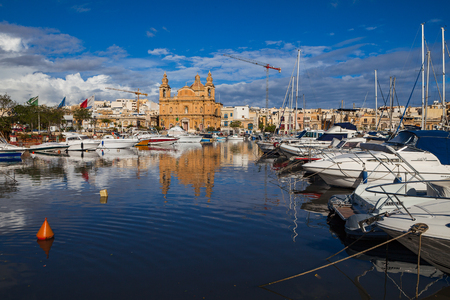 MSIDA, MALTA - OCTOBER 19, 2016: The beautiful Parish Church at sunny day with harbor at the foreground.のeditorial素材