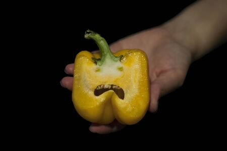 hand holds sweet yellow Bell pepper sliced in half on a black backgroundの写真素材