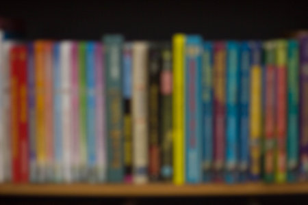 Blurred background with colorful books, university or college textbooks and fiction. Bookshelf at...