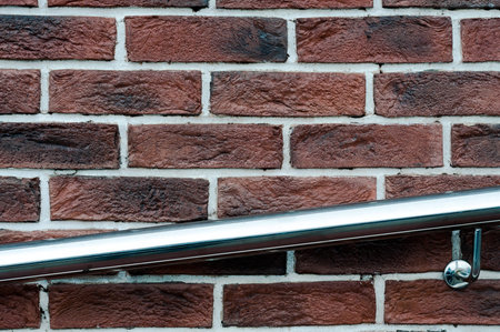 Red grunge brick wall with metal handrail, abstract background texture with old dirty and vintage...