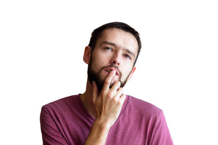 Portrait of the young thinking man looks up with hand near face - isolated on white.