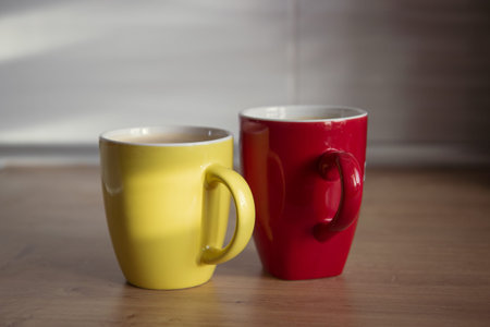 Two cups yellow and red of cappuccino with latte art on wooden background. Beautiful foam, greenery...
