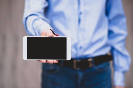 Business man holds and shows mobile phone. Bearded man in suit showing smart phone with blank screen. Business, communication, internet, technology concept.の写真素材