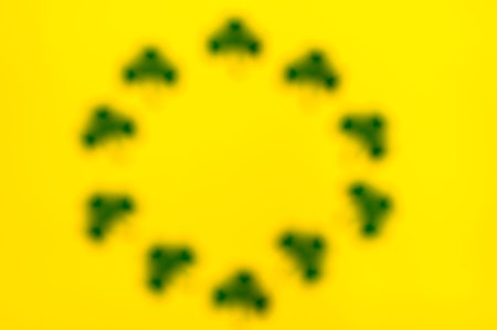 Happy Saint Patrick's of handmade paper clover leaves on yellow background with copy space. Blurred.