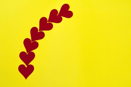 Romantic love concept background with copy space for text and red paper hearts laying on a yellow background. Beautiful Valentines minimalist hipsters cardの写真素材