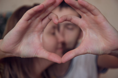Closeup of couple making heart shape with hands.