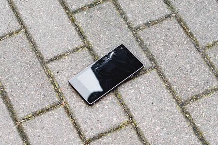 Phone with broken screen on asphalt. Someone dropped deviceの写真素材