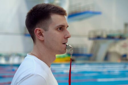 Handsome trainer in white T-shirt standing at the swimming poolの写真素材