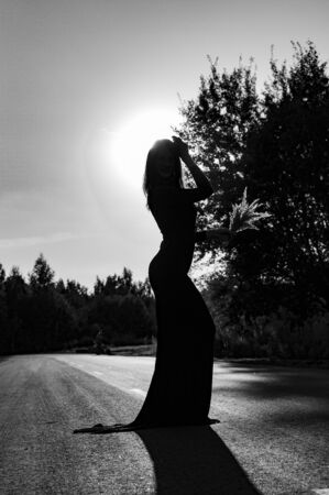 Stylish girl in long dress posing in sunset. black and white photographyの写真素材