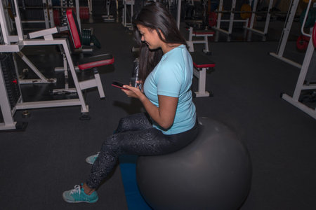 Active girl with smartphone listening to music in gym
