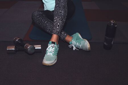 Sport woman sitting and resting after workout or exercise in fitness gym with protein shake or drinking water on floor. Relaxの写真素材