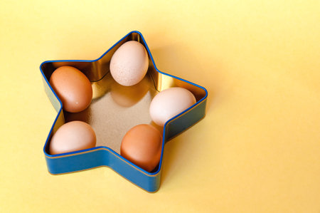 Easter eggs in a star shaped box on yellow color background with copy space