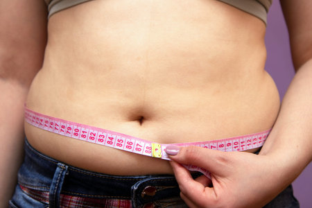 Thick woman measuring thick belly pink measuring tape on white background