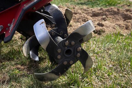Farmer plows the land with a cultivator, preparing it for planting vegetables, on a sunny day gardenの写真素材