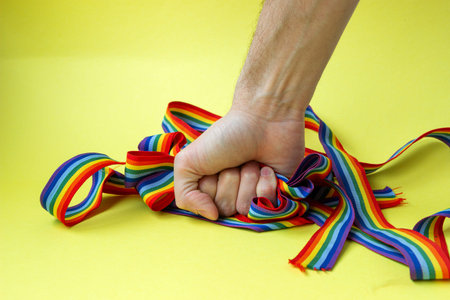 Homophobia. Stop LGBT Pride. Man squeezes in fist rainbow LGBT ribbons in his hand