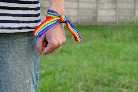 man showing hand with rainbow ribbon. concept of LGBT pride, rights campaign, equality in modern...