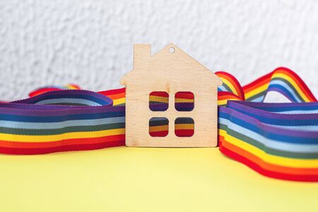 mini toy wooden house and lgbt rainbow ribbbon on yellow background, copy spaceの写真素材