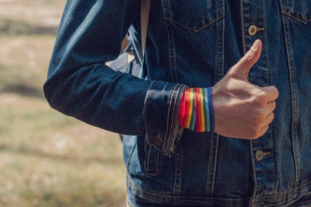 man showing hand with rainbow ribbon with thumbs up. concept of LGBT pride, rights campaign, equality in modern society.の写真素材