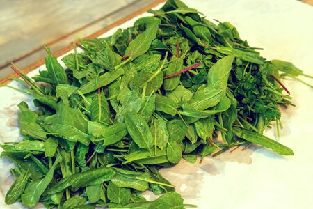 Sorrel and parsley lie and dry on a white tablecloth on a wooden table. Healthy plants close upの写真素材