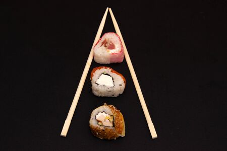 straight parallel vertical lines of sushi and chopstick on black background. sushi rolls patternの写真素材