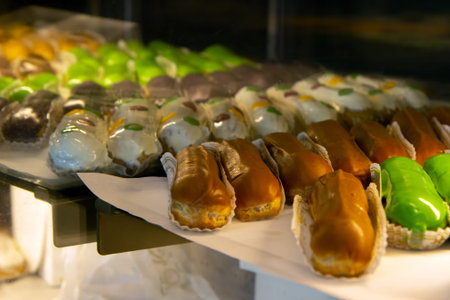 Pastry shop glass display with different colored eclair. selection focus