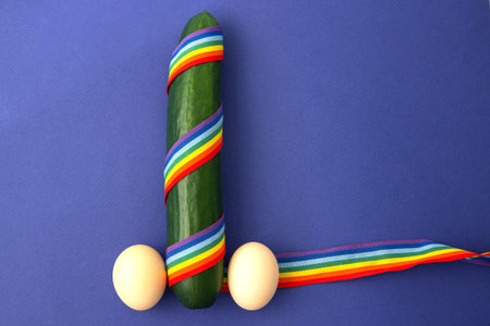 cucumber in rainbow gay ribbon with yats on a blue background. The concept of same-sex gay couples,...