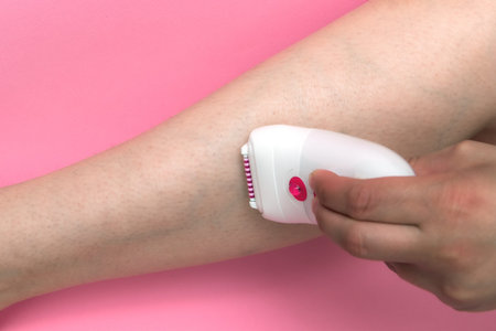 Woman epilating Leg, white electric epilator. close-up female fragment leg shaver shaving. Skin Care and Health. Hair Removal.の写真素材